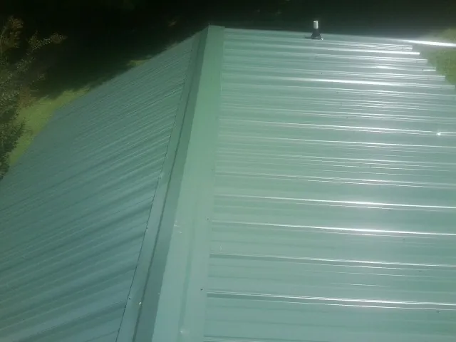 New green metal panels meeting at the ridge of a roof — Flat Roof Repair work by our crew in Osprey