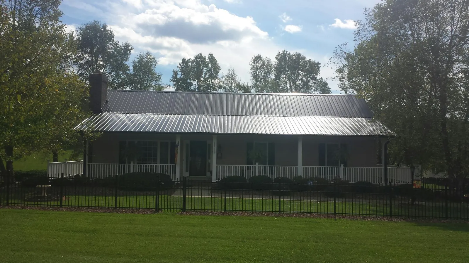 Gray metal roof on a brick ranch with a full width front porch — Gutter Guard Installation work by our crew in Osprey