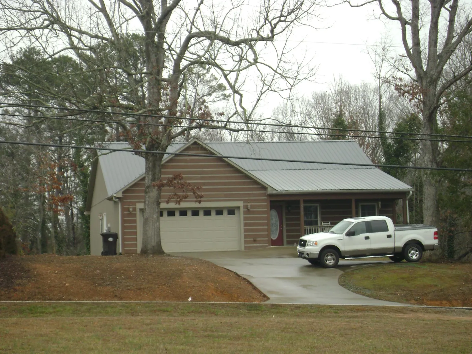Gray metal roof on a log sided house with an attached two car garage in Osprey