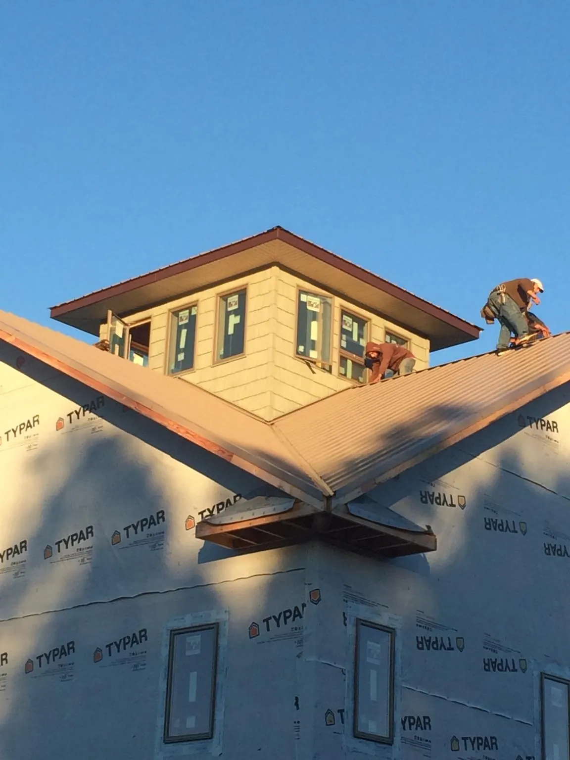 Roofers working around a rooftop cupola on a new metal roof at sunset — Roof Waterproofing in Osprey by Roofing Brothers